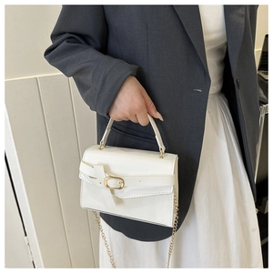 Close-up of elegant white leather handbag with golden oval buckle and chain strap