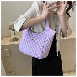 Close-up of lavender quilted tote bag featuring a gold floral logo and puffer design