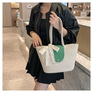Detail of woven straw tote bag with green oval accents and white lace bow decoration