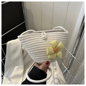 Detail of woven straw bag showing a sunflower fabric charm and pearl clasp closure