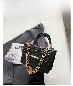 Detail of black quilted patent leather bag featuring gold chain and ruched handle design