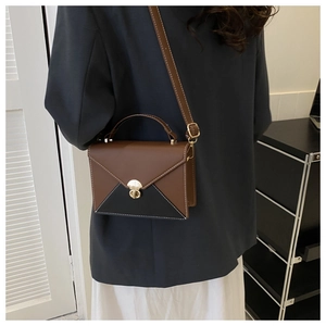 Detail view of contrast stitching and gold lock on a brown patchwork shoulder bag
