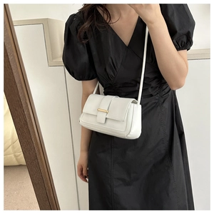 Petit sac bandoulière blanc minimaliste avec boucle dorée porté sur robe noire