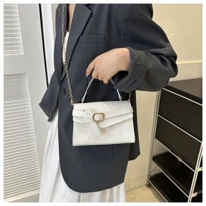 Close-up of white PU leather bag with knotted detail and gold metal chain strap