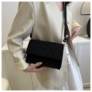 Détail d'un sac bandoulière noir avec texture géométrique et boucles dorées sur modèle