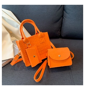 Detailed close-up of orange felt handbag set with quilted texture and gold hardware