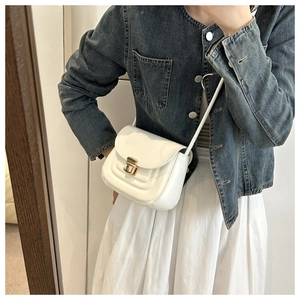 Close-up of white leather crossbody bag with wave texture and gold metal clasp