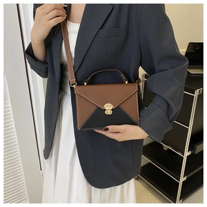 Detail of color-block envelope bag with gold twist lock and fine contrast stitching