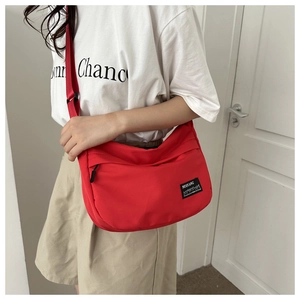 Detail of red oxford nylon crossbody bag featuring adjustable strap and logo patch