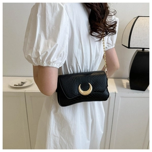 Detail of black crocodile texture shoulder bag with golden crescent buckle and chain strap