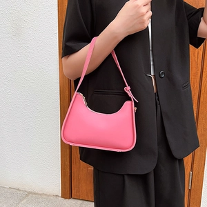 Pink minimalist hobo underarm bag with zipper closure worn by a model in casual attire