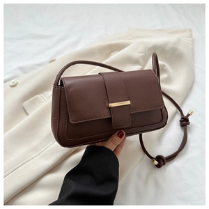 Détail du sac bandoulière marron foncé avec fermoir doré et bandoulière à nœud élégant