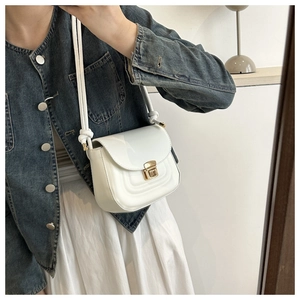 White patent leather crossbody bag with gold metallic lock and knot strap detail