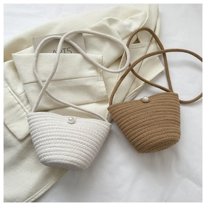 Detail of woven bucket bag featuring elegant pearl closure and sleek shoulder strap