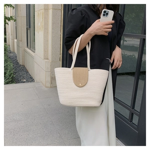 Detailed close-up of the woven texture and tan flap closure on a stylish summer tote bag