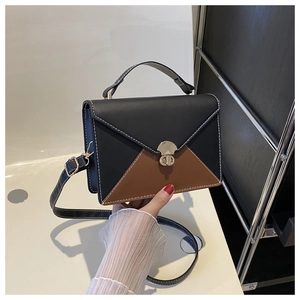 Detail of color-block envelope bag with white stitching and round metal buckle