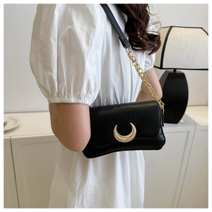 Detail of black crescent bag featuring embossed texture and gold moon metal buckle
