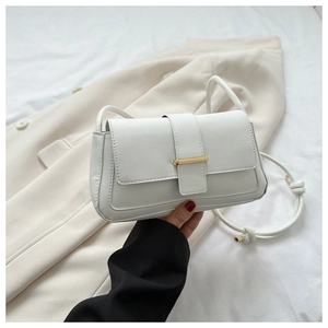 Détail du sac bandoulière en cuir blanc avec boucle dorée et bandoulière à nœuds