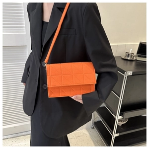 Gros plan sur un sac bandoulière orange en feutre matelassé avec texture géométrique