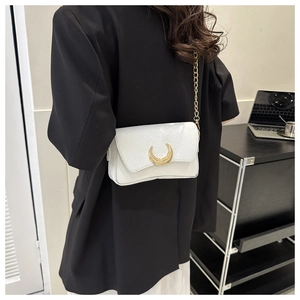 Detail of white embossed leather handbag with gold crescent buckle on a black suit