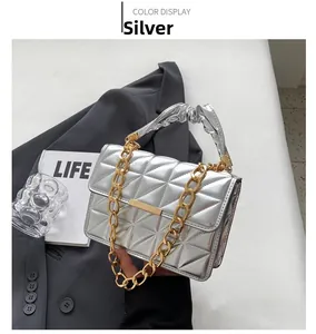 Close-up of a silver quilted handbag featuring metallic triangle patterns and a gold chain