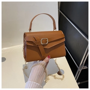Detailed shot of caramel brown leather handbag featuring a gold chain strap and top handle
