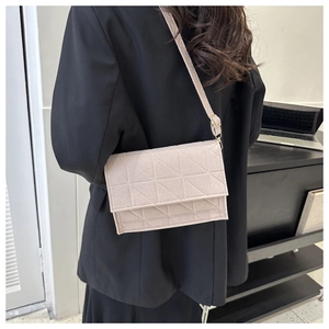 Gros plan détaillé d'un sac bandoulière matelassé beige dans un cadre de bureau moderne