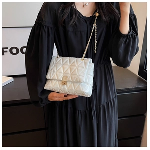 Detailed view of white quilted crossbody bag featuring triangular stitching and gold chain