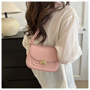 Detail of pink shoulder bag featuring quilted arc patterns and metallic buckle closure
