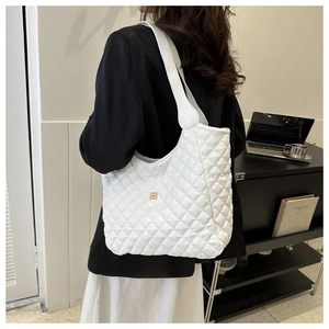 Detail of white quilted tote bag featuring metallic logo and reinforced wide shoulder strap