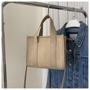 Dettaglio della borsa tote in paglia intrecciata con trama beige e manici in ecopelle