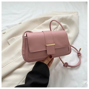 Détail d'un sac bandoulière rose pâle avec boucle dorée et bandoulière à nœuds élégants