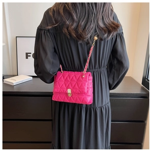Detail view of rose pink quilted crossbody bag with gold chain strap on black dress