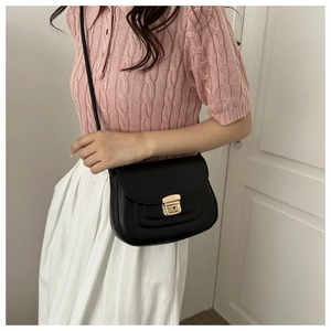 Close-up of minimalist black half-moon shoulder bag with golden metal buckle and PU leather