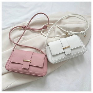 Détail de sacs à bandoulière rectangulaires rose et blanc avec boucle dorée sur blazer