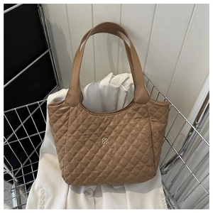 Detail showing the brown quilted leather tote bag with a golden floral emblem in a metal basket