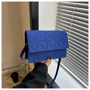 Gros plan sur un sac bandoulière en feutre bleu roi avec motif matelassé géométrique