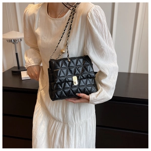 Detail of black quilted leather shoulder bag with gold clasp and chain strap
