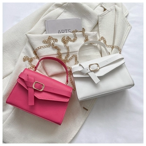 Close-up of minimalist chain crossbody bags in magenta and white with gold hardware