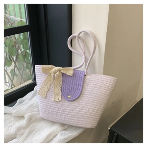 Close-up of a lilac woven tote bag with a cream lace bow and purple flap detail