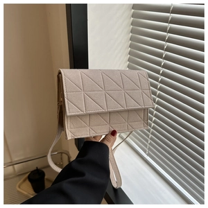 Détail du petit sac carré beige avec surpiqûres triangulaires et bandoulière fine