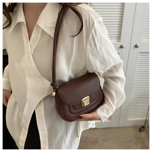 Detail of dark brown crossbody bag with gold metal clasp and premium leather texture