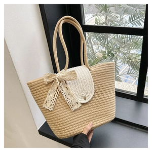 Detailed close-up of a beige straw woven tote bag with white lace bow and round metal stud