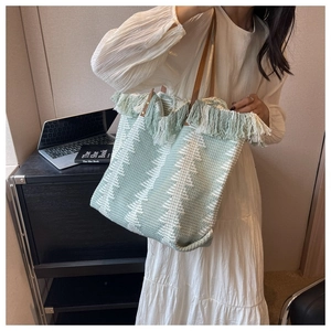 Detail of green knit tote bag with fringe edge and premium brown leather handles