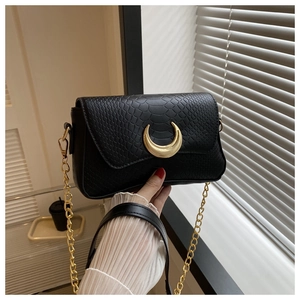 Close-up of black snake texture crescent bag with gold half-moon clasp and fine chain