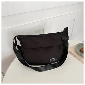 Detail of waterproof nylon shoulder bag with zipper pocket and adjustable strap on white table