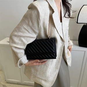 Elegante borsa a tracolla trapuntata nera con catena dorata indossata da una modella