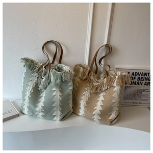 Detail showing handwoven tote bags with fringe trim and brown leather handles in boho style
