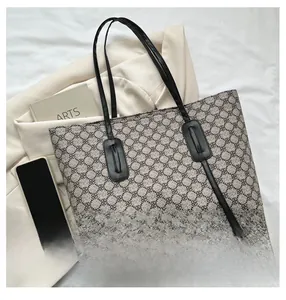 Flat lay of a large geometric pattern tote bag with laptop and phone on white background