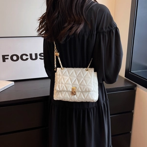 White quilted crossbody bag with gold chain strap and metal ball detail on model